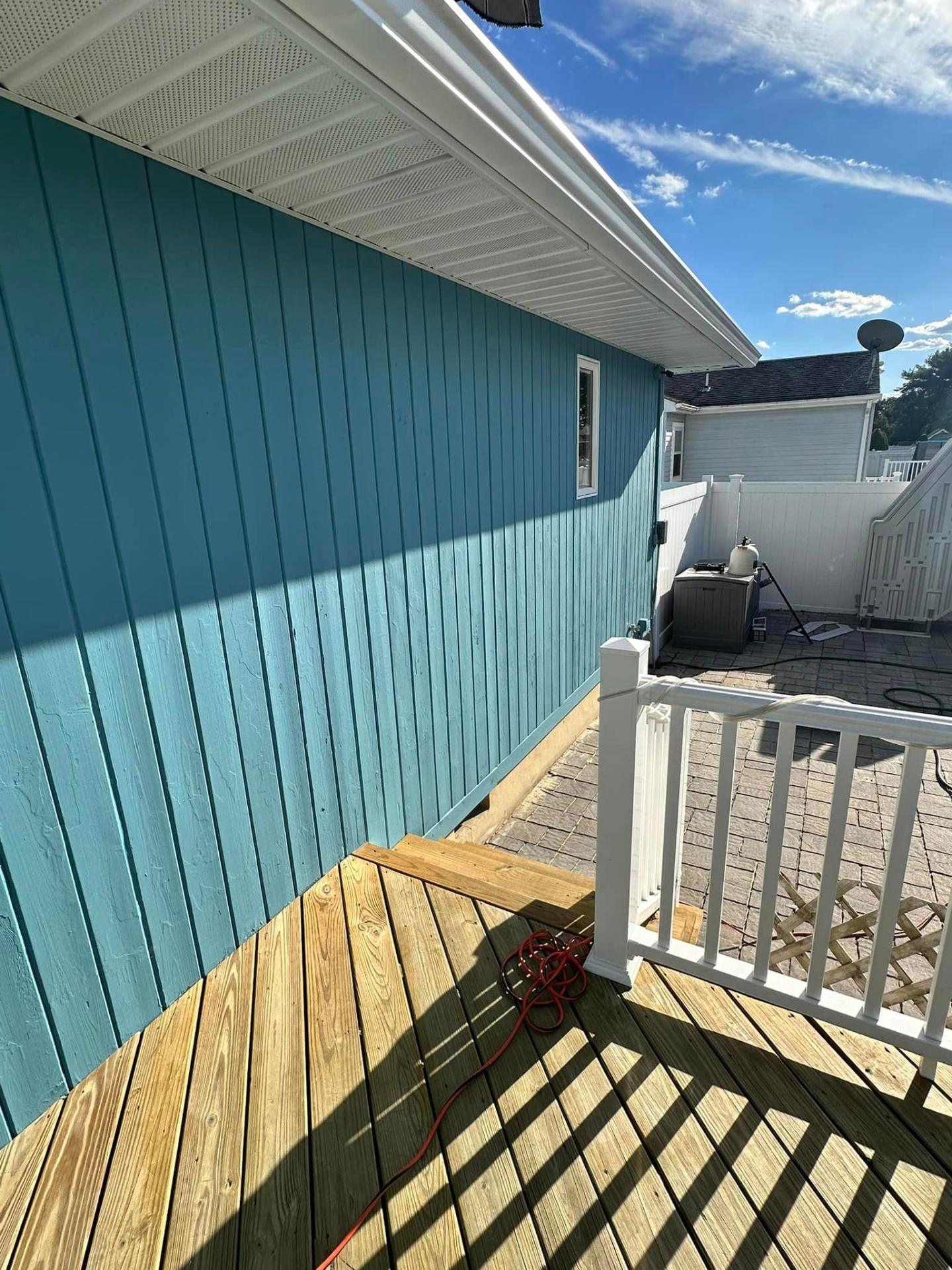 Professional exterior house painting in progress showing blue siding and fresh paint